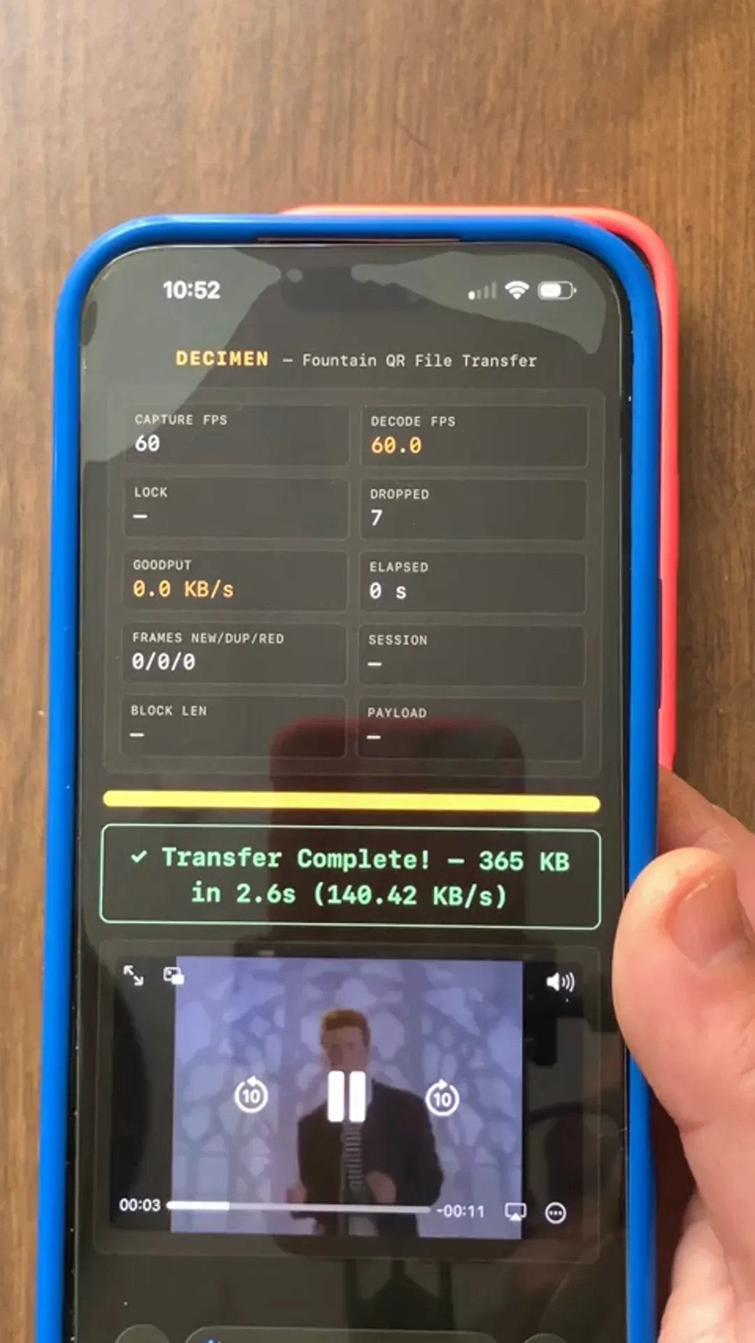 Two phones running DECIMEN, a fountain-coded QR file transfer. The sender fills its screen with dense QR frames at 60 FPS; the receiver's status panel reads 64% of 1.0 MB received, decoding 4.8 FPS, goodput 140.5 KB/s.